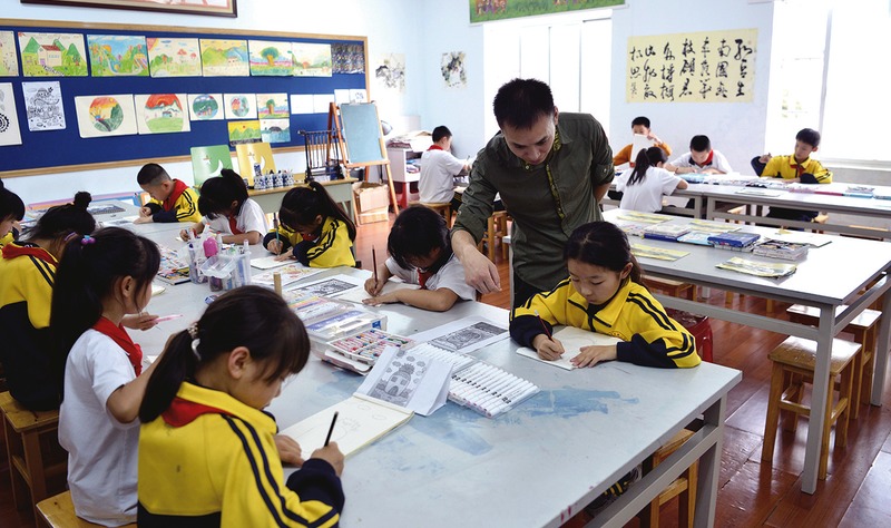 中国小学美术课堂里，五年级学生正在老师指导下安静创作